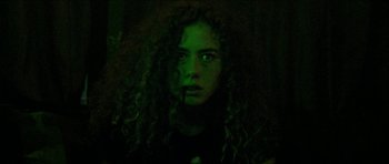 Movie still from “Bliss” (2019), directed by Joe Begos – A woman with curly red hair is staring at the camera; Close Up shot, Low angle