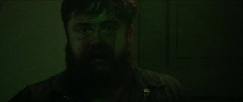Movie still from “Bliss” (2019), directed by Joe Begos – A man with a long beard is looking at the camera; Close Up shot, Low angle