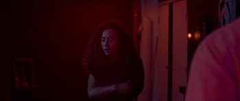 Movie still from “Bliss” (2019), directed by Joe Begos – A man with long hair standing in a dark room; Medium shot, High angle