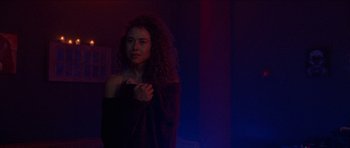 Movie still from “Bliss” (2019), directed by Joe Begos – A woman with curly red hair standing in a dark room; Medium shot, Low angle