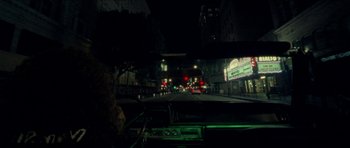 Movie still from “Bliss” (2019), directed by Joe Begos – A view from inside a car at night of a city street; Wide shot, High angle