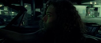 Movie still from “Bliss” (2019), directed by Joe Begos – A man with curly hair is looking into the dark; Close Up shot, Over the shoulder angle