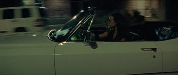 Movie still from “Bliss” (2019), directed by Joe Begos – A woman sitting in the driver's seat of a car at night; Medium shot, Low angle