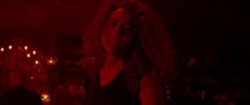Movie still from “Bliss” (2019), directed by Joe Begos – A woman with curly red hair standing in a room; Close Up shot, Low angle