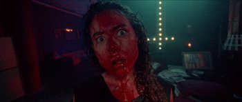 Movie still from “Bliss” (2019), directed by Joe Begos – A woman with red paint all over her face; Close Up shot, Low angle