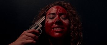 Movie still from “Bliss” (2019), directed by Joe Begos – A woman with blood on her face holding up a gun; Close Up shot, Overhead angle