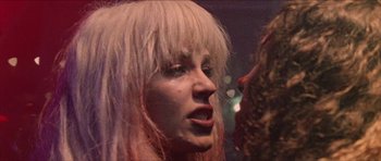 Movie still from “Bliss” (2019), directed by Joe Begos – A person with long blonde hair; Close Up shot, Over the shoulder angle