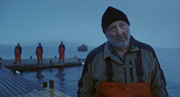 An older man standing in front of a body of water