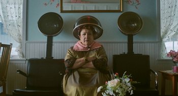 An older woman sitting in front of a bunch of hair dryers
