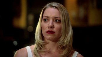 A woman with blonde hair and red lipstick looking to her left