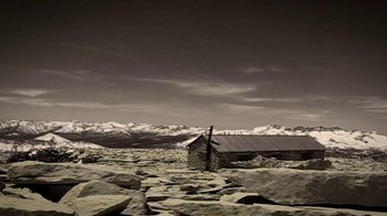 Movie still from “Blue Jay” (2016), directed by Alex Lehmann – A small hut on a rocky hill with a mountain range in the background; Extreme Wide shot, High angle