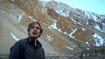 Movie still from “Blue Jay” (2016), directed by Alex Lehmann – A man standing in front of a snowy mountain range; Close Up shot, Low angle