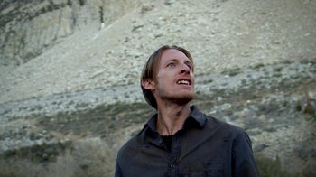 Movie still from “Blue Jay” (2016), directed by Alex Lehmann – A man with long brown hair wearing a black shirt; Close Up shot, Low angle
