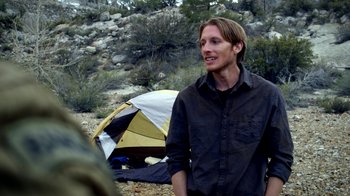 Movie still from “Blue Jay” (2016), directed by Alex Lehmann – A man standing in front of a tent in the woods; Medium shot, Over the shoulder angle