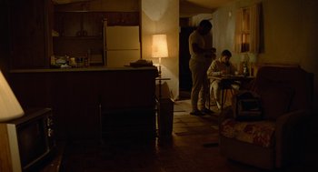 Movie still from “Bones and All” (2022), directed by Luca Guadagnino – Two people are sitting in the dark in a kitchen; Wide shot, Low angle