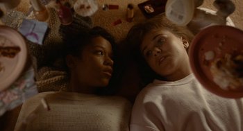 Movie still from “Bones and All” (2022), directed by Luca Guadagnino – Two women laying on the floor next to each other; Medium shot, Overhead angle
