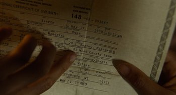 Movie still from “Bones and All” (2022), directed by Luca Guadagnino – A person's hands on a birth certificate; Extreme Close Up shot, High angle