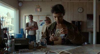 Movie still from “Bones and All” (2022), directed by Luca Guadagnino – A woman holding a dollar bill in her hands; Medium shot, Over the shoulder angle