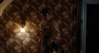 Movie still from “Bones and All” (2022), directed by Luca Guadagnino – A man standing in front of a wall with flowers on it; Medium shot, Low angle