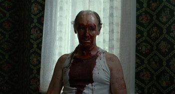 Movie still from “Bones and All” (2022), directed by Luca Guadagnino – A man with blood all over his face and chest; Medium shot, Over the shoulder angle