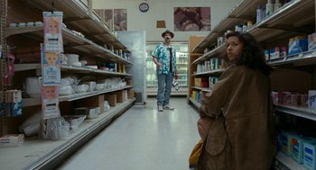 Movie still from “Bones and All” (2022), directed by Luca Guadagnino – A man and a woman are standing in a grocery store; Wide shot, Low angle