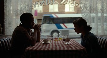 Movie still from “Bones and All” (2022), directed by Luca Guadagnino – Two people are sitting at a table with food and drinks; Medium shot, Over the shoulder angle
