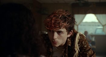 Movie still from “Bones and All” (2022), directed by Luca Guadagnino – A young man with curly red hair looking at the camera; Close Up shot, Over the shoulder angle
