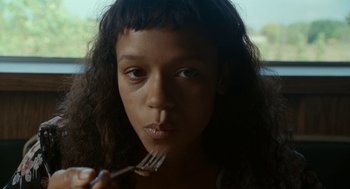 Movie still from “Bones and All” (2022), directed by Luca Guadagnino – A young woman holding a fork in her mouth; Close Up shot, High angle