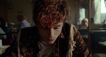 Movie still from “Bones and All” (2022), directed by Luca Guadagnino – A man with red hair and a brown shirt; Close Up shot, Over the shoulder angle