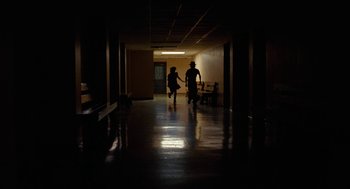 Movie still from “Bones and All” (2022), directed by Luca Guadagnino – Two people are walking in a dark hallway; Wide shot, Low angle