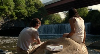 Movie still from “Bones and All” (2022), directed by Luca Guadagnino – A man and a woman sitting next to a waterfall; Wide shot, Over the shoulder angle