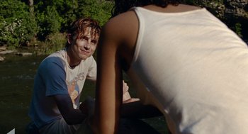 Movie still from “Bones and All” (2022), directed by Luca Guadagnino – A man and a woman sitting on the grass; Medium shot, Over the shoulder angle