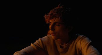 Movie still from “Bones and All” (2022), directed by Luca Guadagnino – A man with red hair is sitting in the dark; Close Up shot, Over the shoulder angle