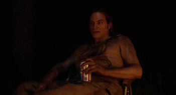 Movie still from “Bones and All” (2022), directed by Luca Guadagnino – A man sitting in a chair holding a can of beer; Medium shot, Low angle