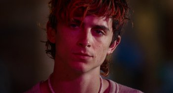 Movie still from “Bones and All” (2022), directed by Luca Guadagnino – A person wearing a pink shirt; Close Up shot, Low angle