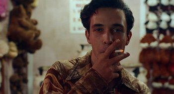 Movie still from “Bones and All” (2022), directed by Luca Guadagnino – A young man is smoking a cigarette in a room; Close Up shot, Over the shoulder angle