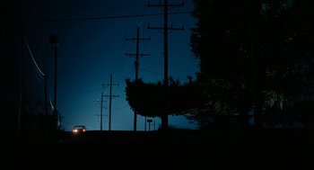 Movie still from “Bones and All” (2022), directed by Luca Guadagnino – A car driving down a road near power lines at night; Extreme Wide shot, Low angle