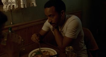 Movie still from “Bones and All” (2022), directed by Luca Guadagnino – A man sitting in front of a plate of food; Close Up shot, High angle