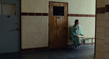 Movie still from “Bones and All” (2022), directed by Luca Guadagnino – A woman sitting on a bench in front of a door; Wide shot, Over the shoulder angle