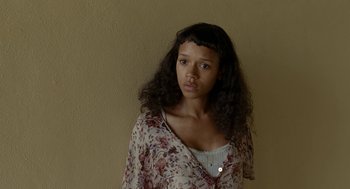 Movie still from “Bones and All” (2022), directed by Luca Guadagnino – A young woman with long black hair wearing a floral dress; Close Up shot, Low angle