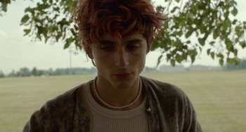 Movie still from “Bones and All” (2022), directed by Luca Guadagnino – A young man with red hair and a white shirt; Close Up shot, Over the shoulder angle