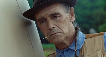 Movie still from “Bones and All” (2022), directed by Luca Guadagnino – An older man with a hat and a cigarette in his mouth; Close Up shot, Over the shoulder angle