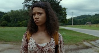 Movie still from “Bones and All” (2022), directed by Luca Guadagnino – A woman with a backpack standing in a field; Close Up shot, Low angle