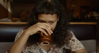 Movie still from “Bones and All” (2022), directed by Luca Guadagnino – A woman drinking a cup of coffee from a brown mug; Close Up shot, Over the shoulder angle