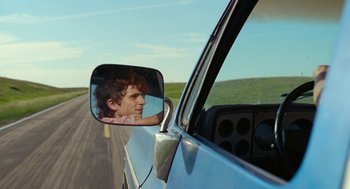 Movie still from “Bones and All” (2022), directed by Luca Guadagnino – A side view mirror of a car with a man in the reflection of the mirror; Close Up shot, Over the shoulder angle