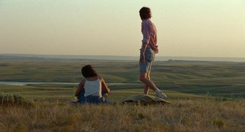 Movie still from “Bones and All” (2022), directed by Luca Guadagnino – Two people sitting in a field looking out at the sky; Wide shot, Over the shoulder angle