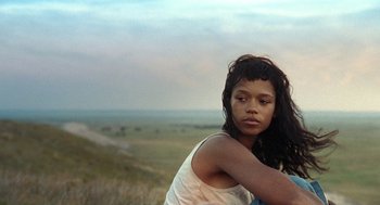 Movie still from “Bones and All” (2022), directed by Luca Guadagnino – A young woman is standing in a field; Medium shot, Low angle