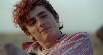 Movie still from “Bones and All” (2022), directed by Luca Guadagnino – A young man with red curly hair is smiling; Close Up shot, Over the shoulder angle