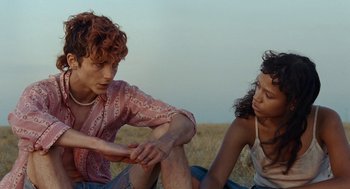 Movie still from “Bones and All” (2022), directed by Luca Guadagnino – Two people sitting on the ground in a field; Medium shot, Over the shoulder angle