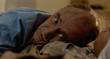 Movie still from “Bones and All” (2022), directed by Luca Guadagnino – An older man laying on the ground with his head on a blanket; Close Up shot, High angle
